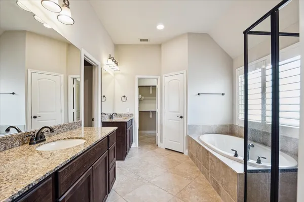 a large bathroom with a granite countertop tub sink and mirror