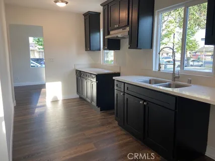 a kitchen with stainless steel appliances granite countertop a sink dishwasher a stove and a microwave oven with wooden floor