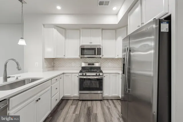 a kitchen with white cabinets stainless steel appliances and a sink