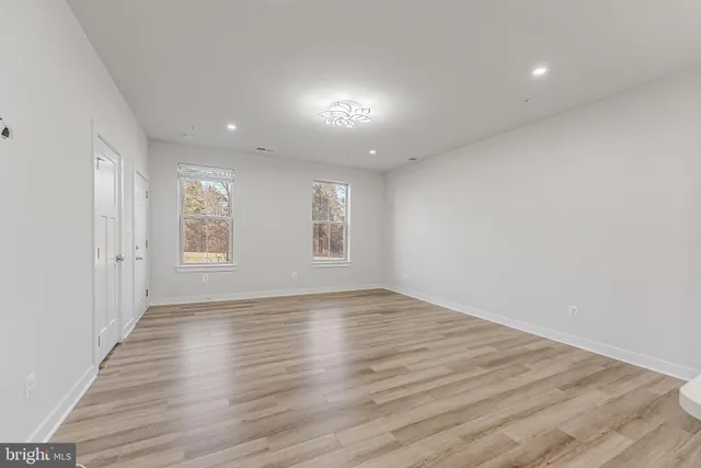 a view of an empty room with wooden floor and windows