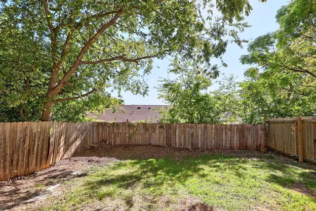 a backyard of a house with lawn chairs and wooden fence