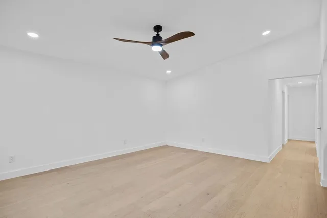 an empty room with windows and ceiling fan