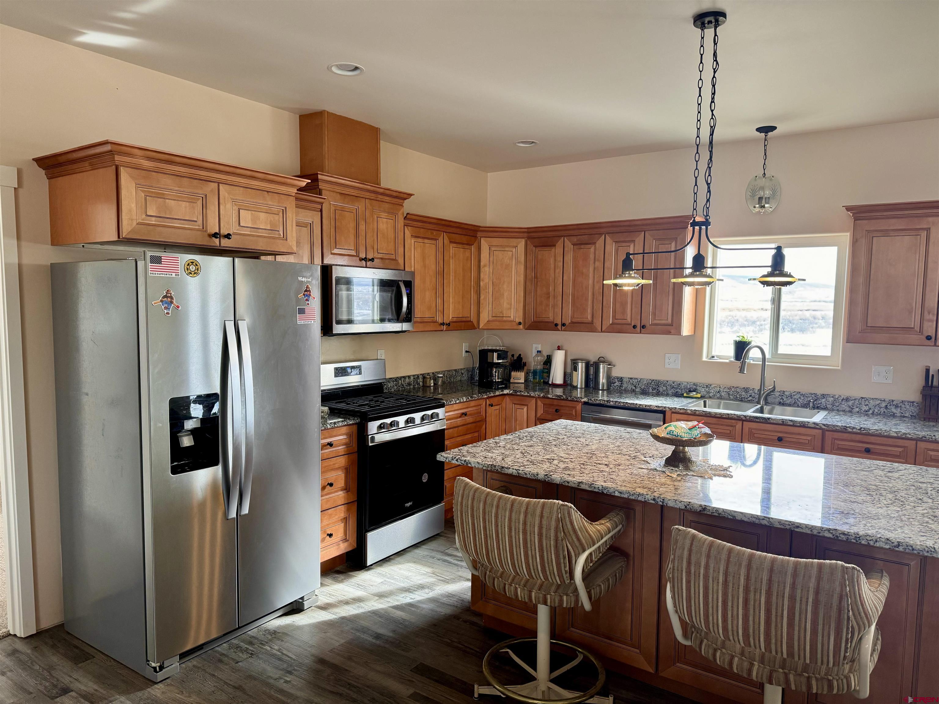23184 D50 Road Delta, CO 81416 - Photo 8 of 23 a kitchen with stainless steel appliances granite countertop a refrigerator a sink dishwasher a stove a dining table and chairs with wooden floor