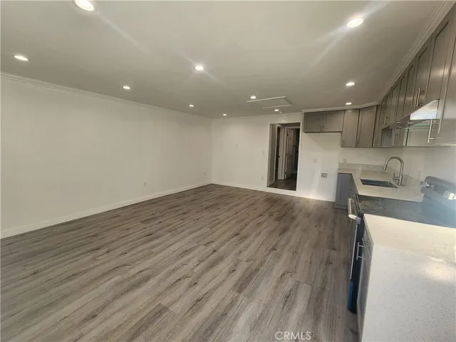 a view of a kitchen with kitchen island a sink wooden floor and a refrigerator