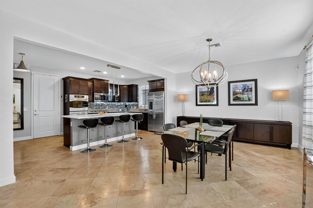 591 Northwest Library Commons Way Boca Raton, FL 33432 - Photo 25 of 75 a open kitchen with stainless steel appliances kitchen island granite countertop a table and chairs in it