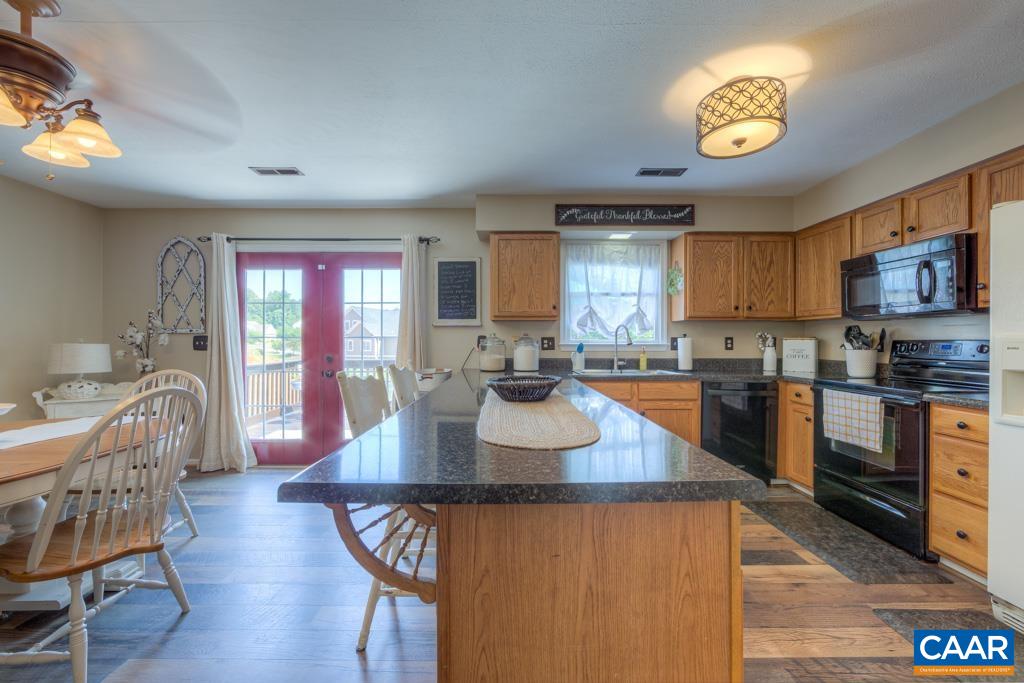 235 Spring Oaks Lane Ruckersville, VA 22968 - Photo 14 of 44 a kitchen with stainless steel appliances granite countertop a stove top oven a sink dishwasher a dining table and chairs with wooden floor