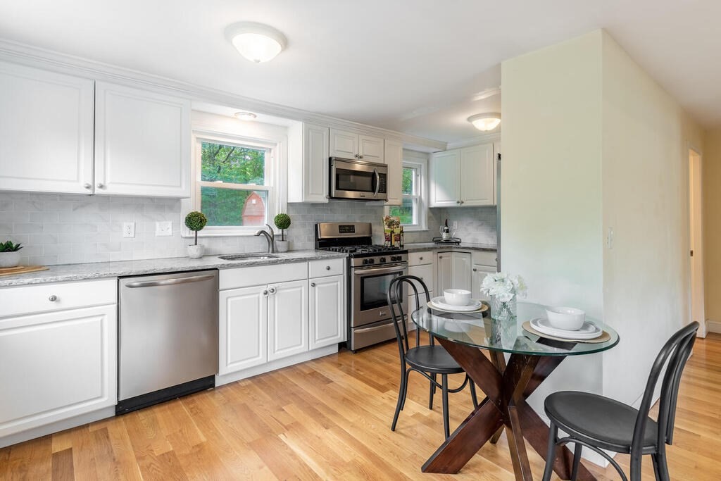 18 Woodbury Road Billerica, MA 01821 - Photo 12 of 30 a kitchen with a table chairs microwave and cabinets