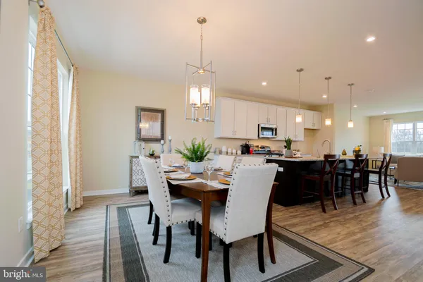 a dining room with wooden floor a chandelier a wooden table and chairs