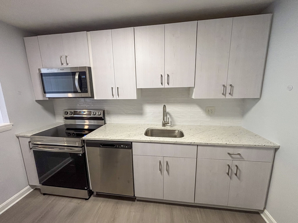 505 Washington, Unit 46 Chelsea, MA 02150 - Photo 4 of 16 a kitchen with white cabinets and stainless steel appliances