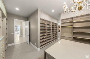 1141 East Lost Ridge Drive Washington, UT 84780 - Photo 72 of 108 Expansive walk-in closet featuring extensive built-in shelving, a central island with a light-toned countertop, recessed lighting, and an ornate chandelier