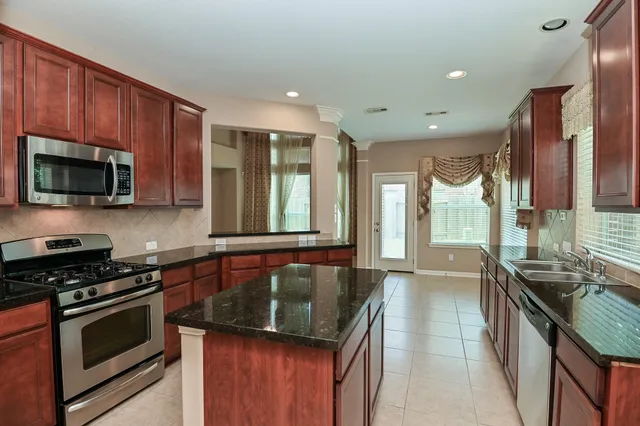 a kitchen with stainless steel appliances granite countertop a stove a sink and a microwave