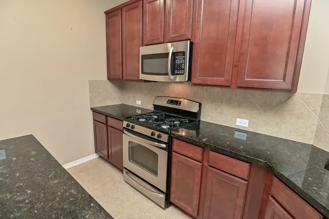 a kitchen with granite countertop wooden cabinets and stainless steel appliances