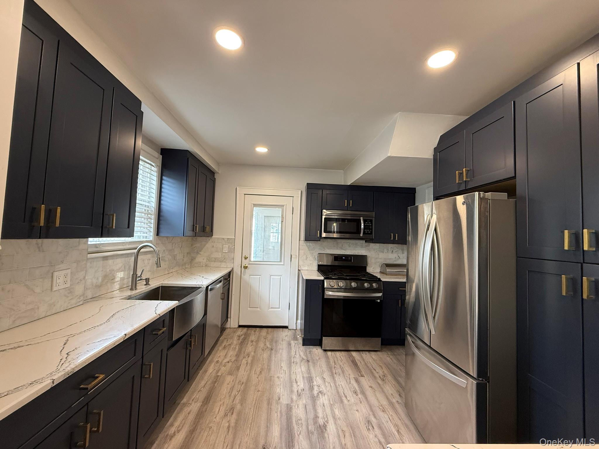 204 North Grove Street Valley Stream, NY 11580 - Photo 7 of 16 Kitchen featuring stainless steel appliances, light wood-style flooring, light stone countertops, recessed lighting, and tasteful backsplash