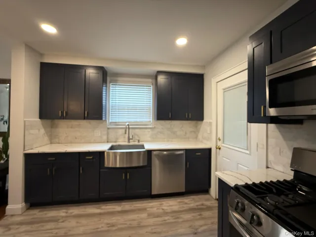 a kitchen with stainless steel appliances granite countertop a sink and a stove top oven with wooden floor
