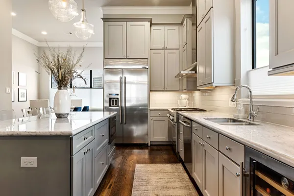 a kitchen with stainless steel appliances kitchen island granite countertop a sink dishwasher a stove and a dining table with wooden floor