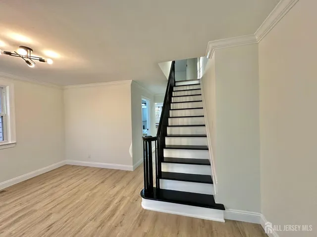 a view of an empty room with wooden floor and stairs