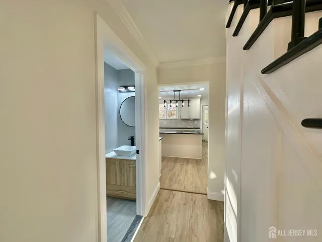 a view of a hallway with wooden floor and a bathroom