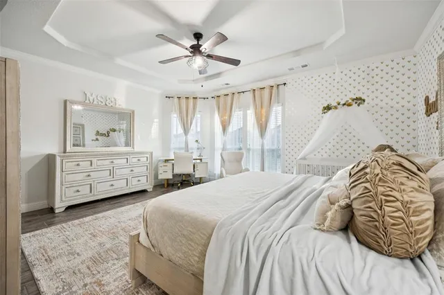 a spacious bedroom with a bed a dresser and a chandelier