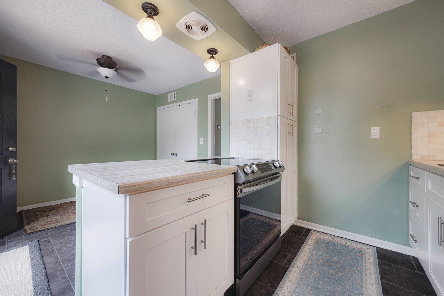 1005 June Road Memphis, TN 38119 - Photo 13 of 22 Kitchen with visible vents, decorative backsplash, a peninsula, range with electric stovetop, and light countertops
