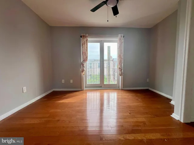 a view of an empty room with window and wooden floor