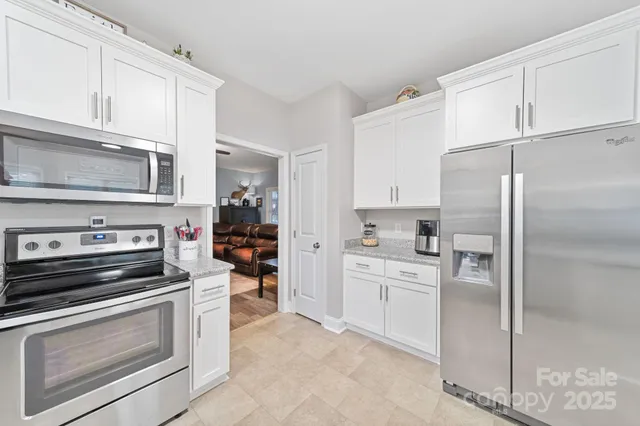 a kitchen with stainless steel appliances granite countertop a refrigerator a sink a stove a dining table and chairs