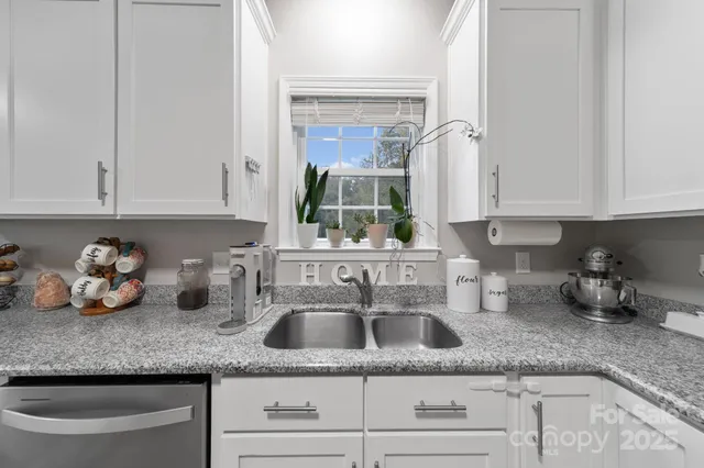a kitchen with granite countertop a stove a sink a dining table and chairs