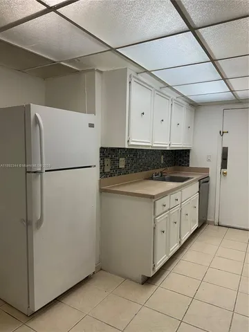 a kitchen with stainless steel appliances granite countertop a refrigerator a sink and white cabinets