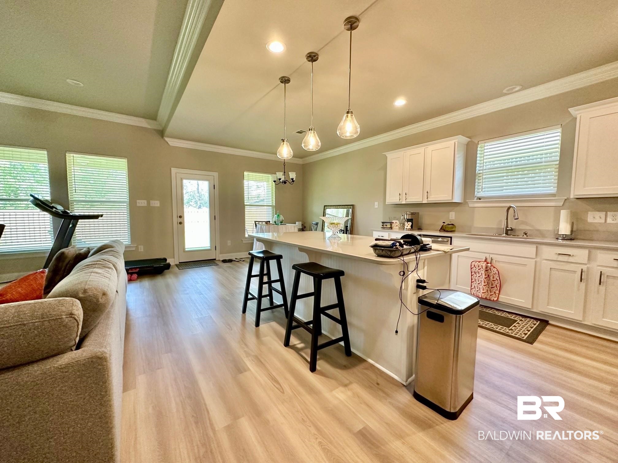 1009 Ruisseau Drive Foley, AL 36535 - Photo 19 of 55 Kitchen featuring hanging light fixtures, ornamental molding, a center island, light wood-type flooring, and white cabinets
