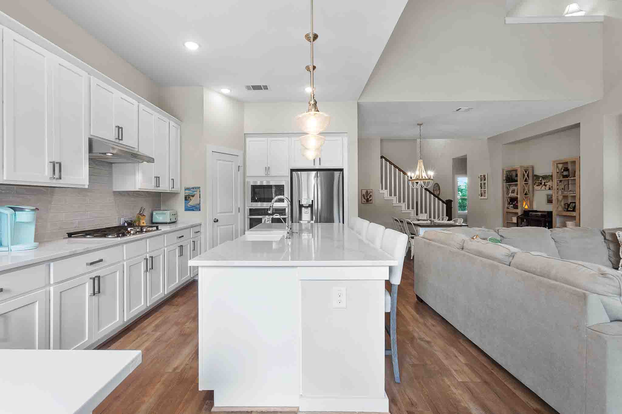 7717 Pace Ravine Drive Lago Vista, TX 78645 - Photo 13 of 39 a large white kitchen with kitchen island a sink a stove and a refrigerator