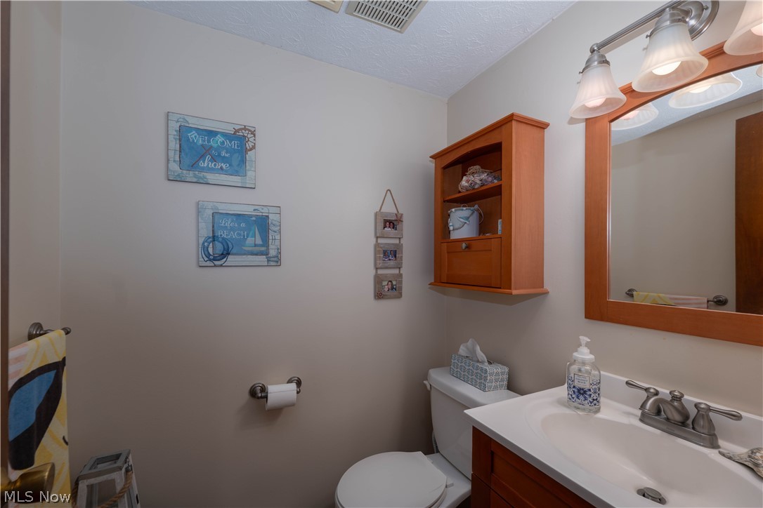 1619 Reed Street Canal Fulton, OH 44614 - Photo 24 of 27 Bathroom featuring a vanity with white countertop, chrome faucet, wall-mounted mirror, and wood-finish wall cabinet
