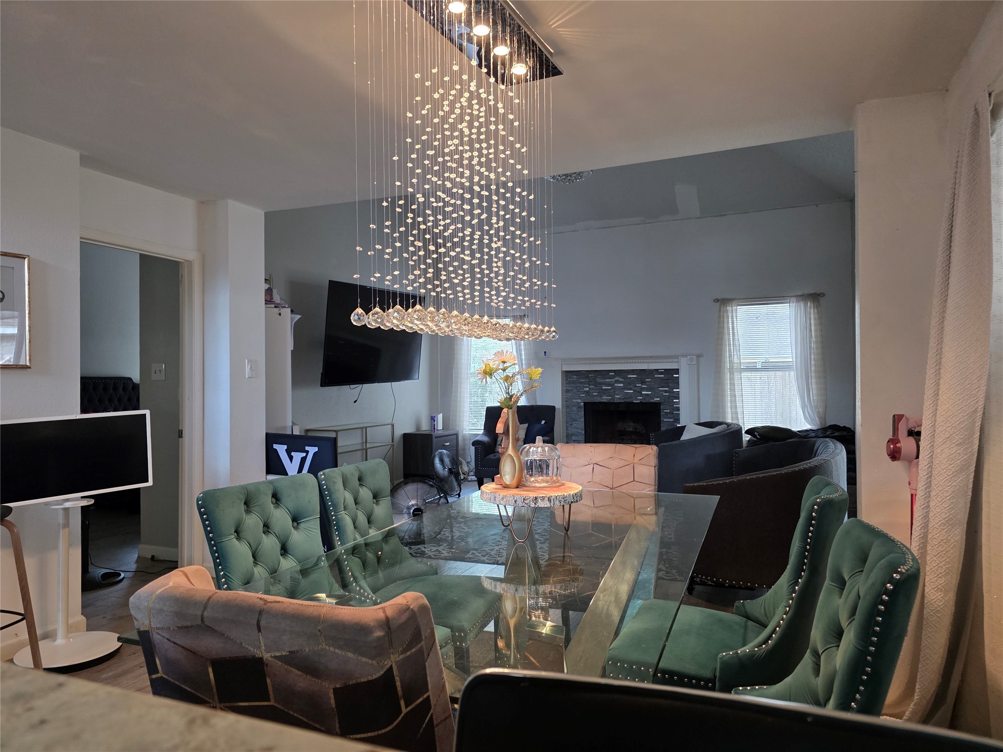15615 Fern Ridge Drive Houston, TX 77084 - Photo 12 of 31 Elegant dining area with a striking modern chandelier, plush seating, and a cozy living space featuring a fireplace and large windows for natural light.