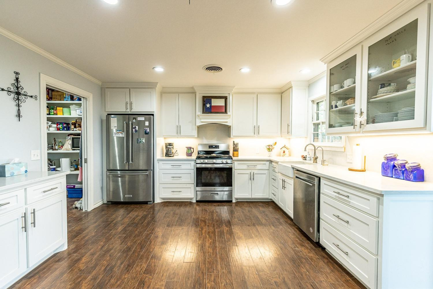 2327 60th Street Lubbock, TX 79412 - Photo 13 of 36 a kitchen with a refrigerator and white cabinets
