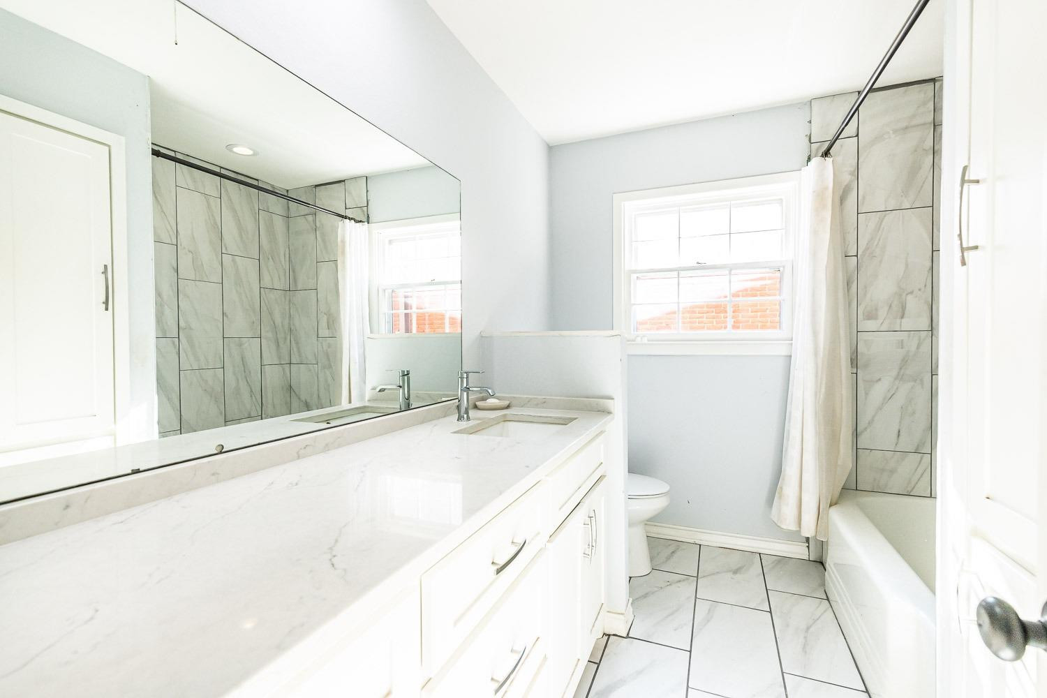 2327 60th Street Lubbock, TX 79412 - Photo 26 of 36 a bathroom with a granite countertop sink a toilet and shower