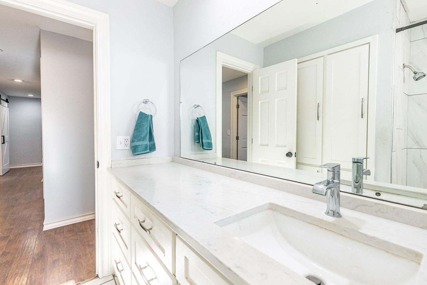 2327 60th Street Lubbock, TX 79412 - Photo 28 of 36 a bathroom with a granite countertop sink and a mirror