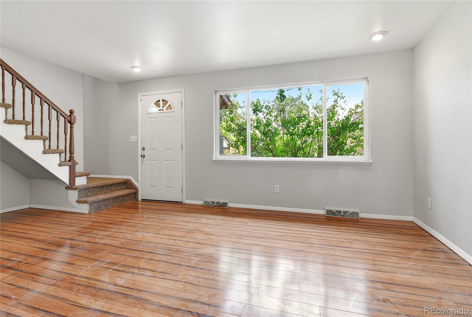 7461 Webster Street Arvada, CO 80003 - Photo 5 of 31 a view of an empty room with wooden floor and a window
