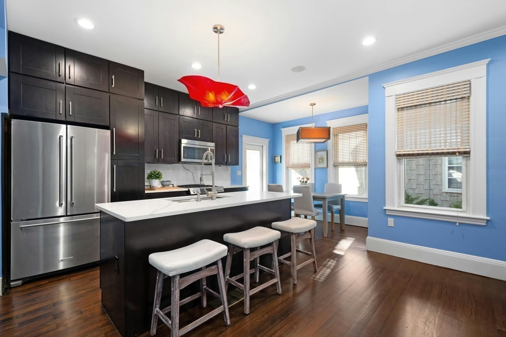 a kitchen with a refrigerator a sink dishwasher a dining table and chairs with wooden floor