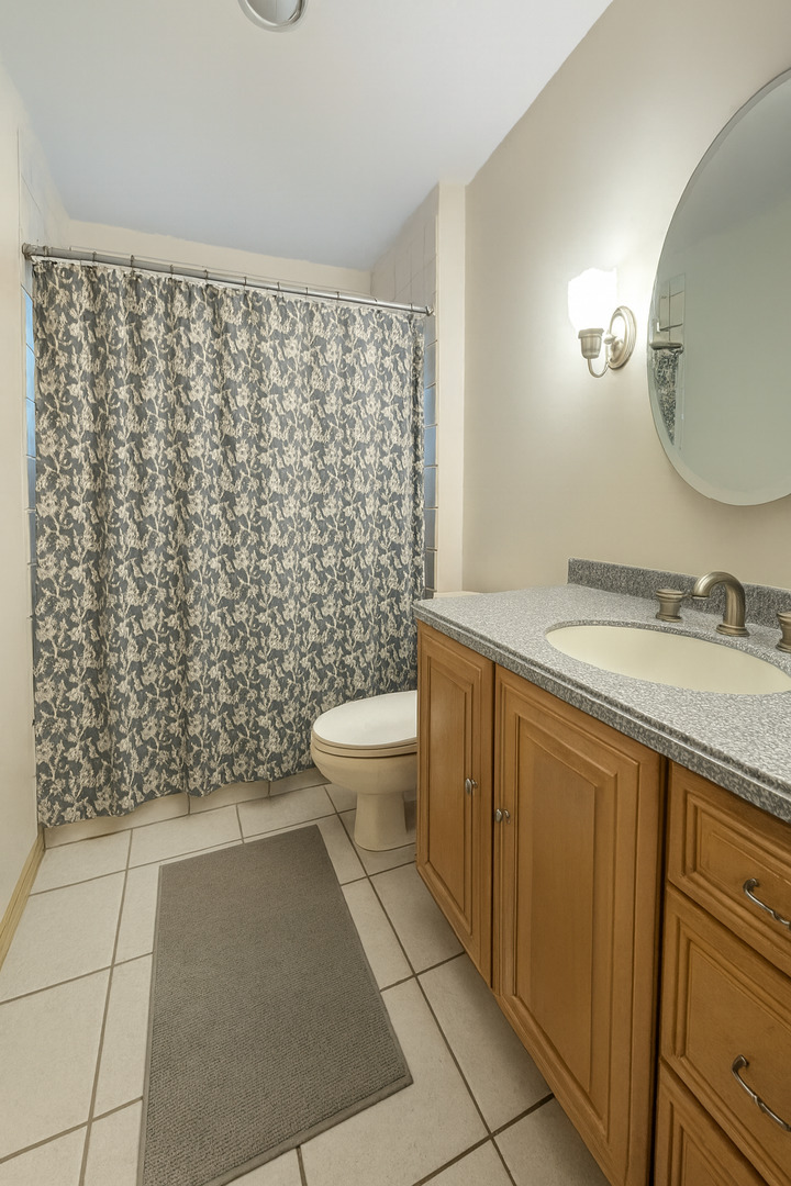 1024 Arbor Lane Glenview, IL 60025 - Photo 8 of 9 a bathroom with a granite countertop toilet a sink a mirror and shower curtain