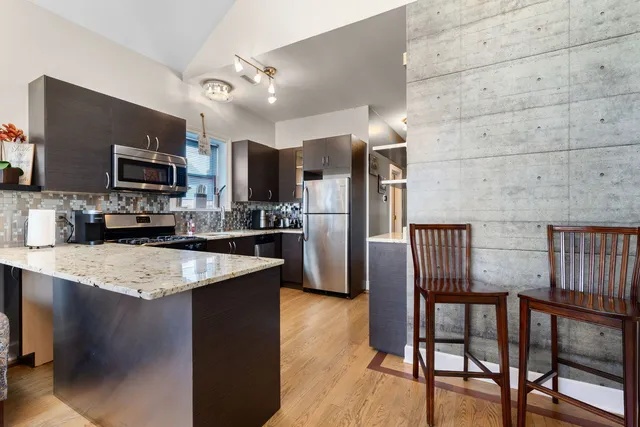 a kitchen with stainless steel appliances granite countertop a stove a refrigerator a microwave a sink and chairs