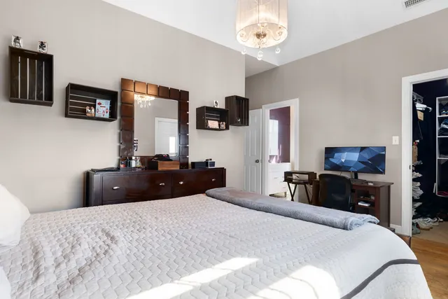 a bedroom with a bed a mirror on dresser and a flat screen tv