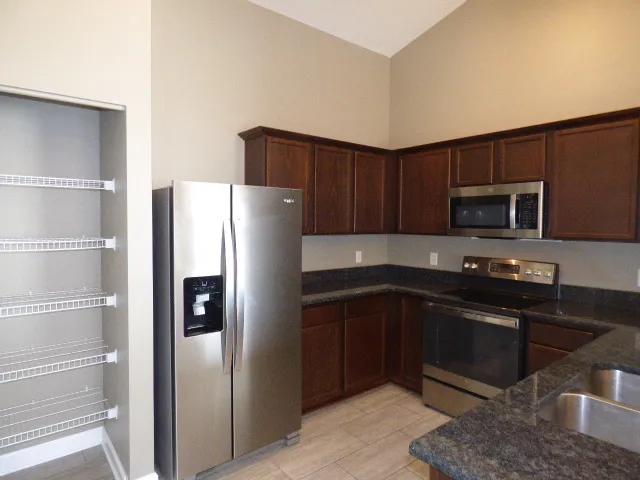 a kitchen with stainless steel appliances granite countertop a refrigerator and a sink