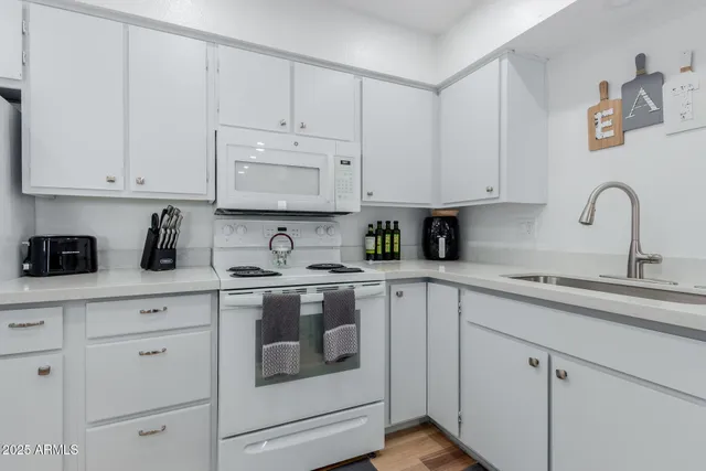 a kitchen with white cabinets and white appliances
