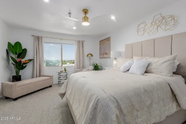 a spacious bedroom with a bed a couch and potted plant on the dresser