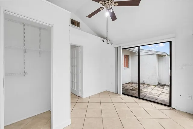 an empty room with windows and ceiling fan