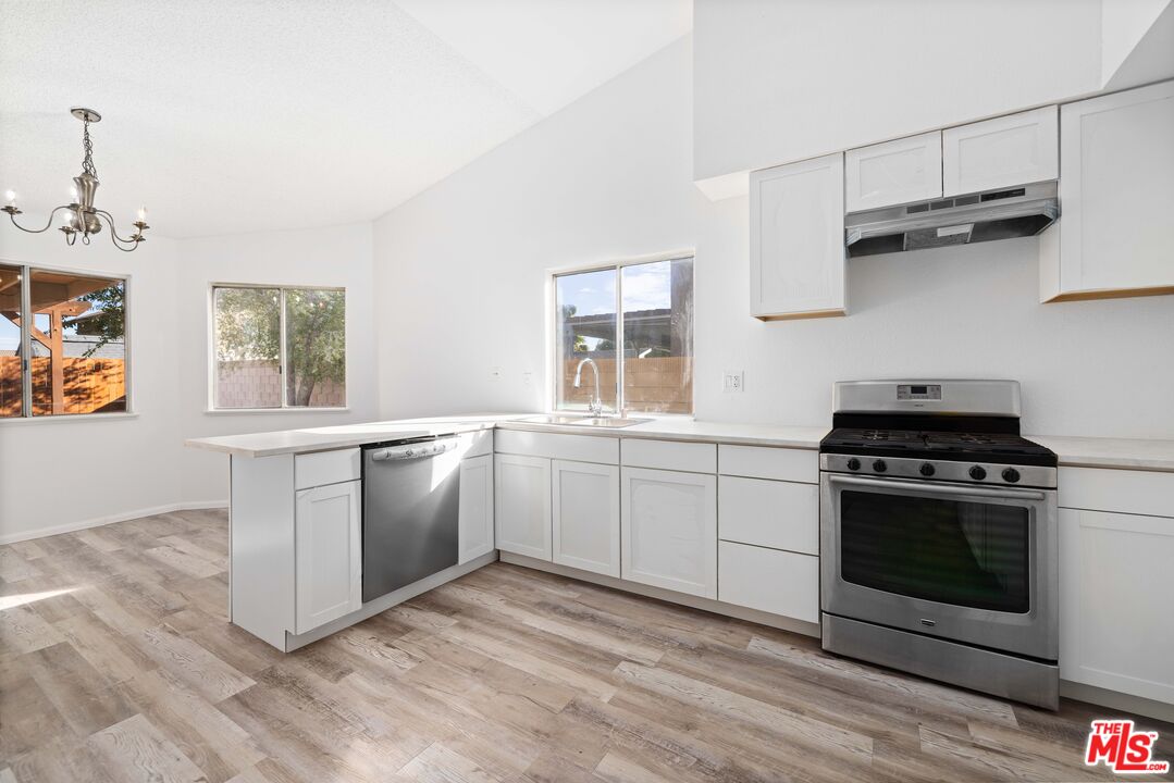 a kitchen with cabinets wooden floor and stainless steel appliances