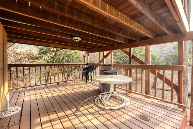 a balcony with wooden floor outdoor seating and yard in the back