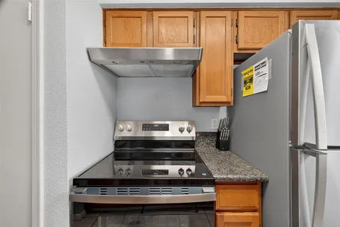 a kitchen with granite countertop cabinets stainless steel appliances a sink and a window