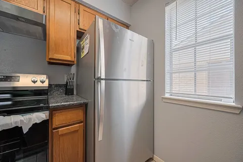 a kitchen with granite countertop wood cabinets and a stove top oven