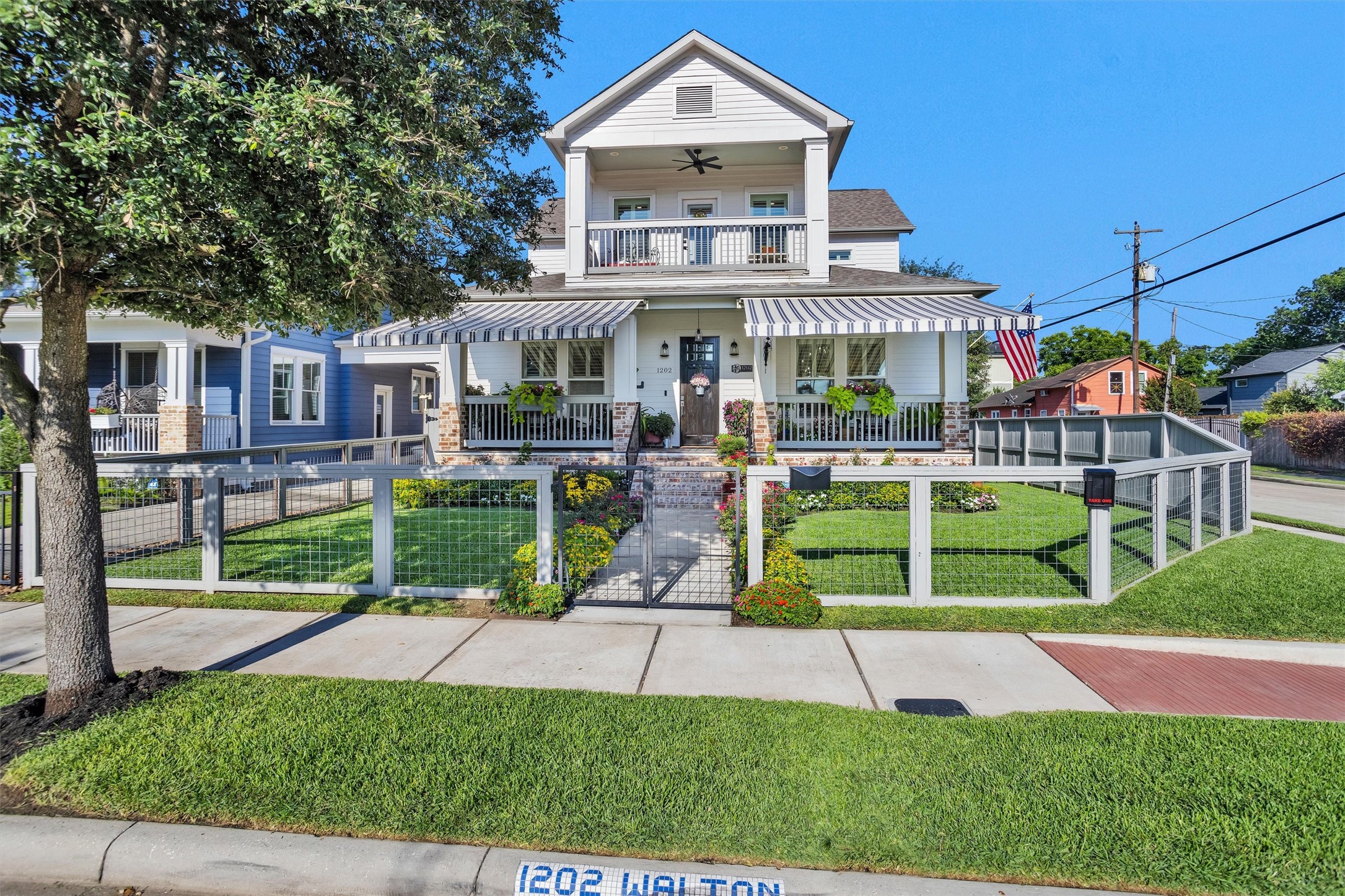 1202 Walton Street Houston, TX 77009 - Photo 2 of 32 Charming Front Elevation Showcasing a Fully Fenced Yard, Beautiful Landscaping, and Retractable Awnings That Add Both Character and Comfort to the Outdoor Living Space.