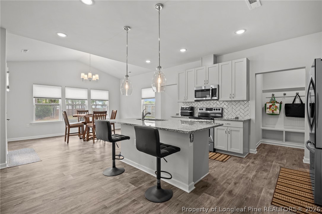 334 Beacon Hl Road Lillington, NC 27546 - Photo 11 of 49 a kitchen with stainless steel appliances granite countertop a stove a refrigerator a oven a sink with a dining table and chairs
