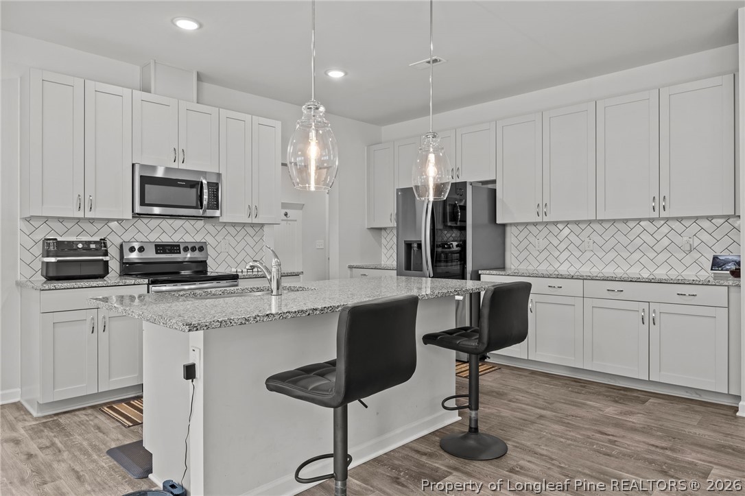 334 Beacon Hl Road Lillington, NC 27546 - Photo 12 of 49 a kitchen with stainless steel appliances granite countertop a stove top oven a refrigerator a sink and white cabinets